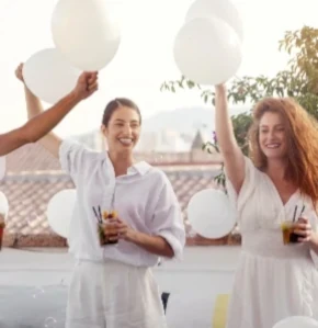 Invités souriants célébrant un événement privé avec des ballons blancs et cocktails. Gustus Traiteur Genève pour vos...