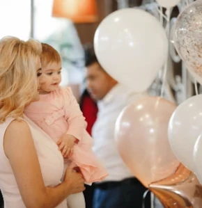 Mère et enfant à une réception familiale avec ballons, pour un anniversaire ou baptême. Évènements privés traiteur Genève.