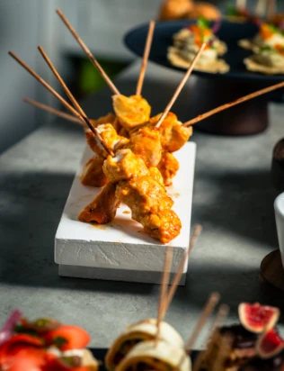 Brochettes de poulet en sauce sur plateau élégant, un service traiteur Genève idéal pour événements et plateaux-repas...