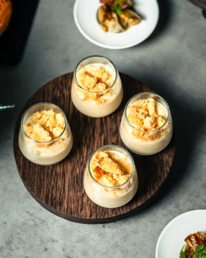 Quatre verrines de desserts raffinés sur un plateau en bois